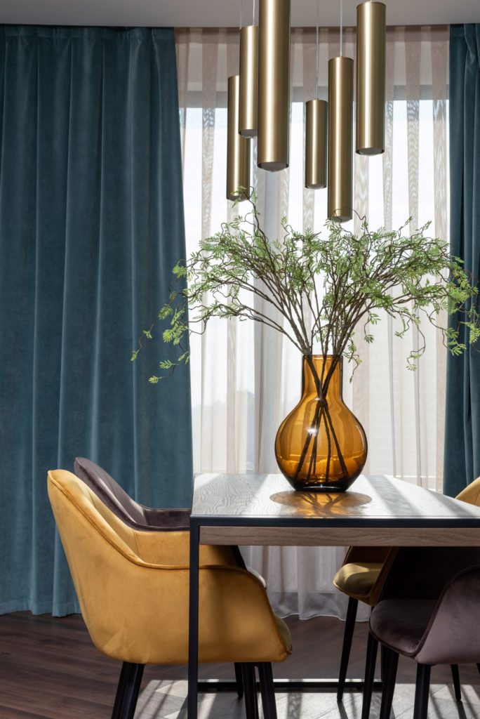 Freshly cut plant in amber vase on modern dining table