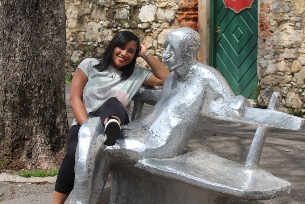 Monique Abbott sitting with statue in Zagreb, Croatia