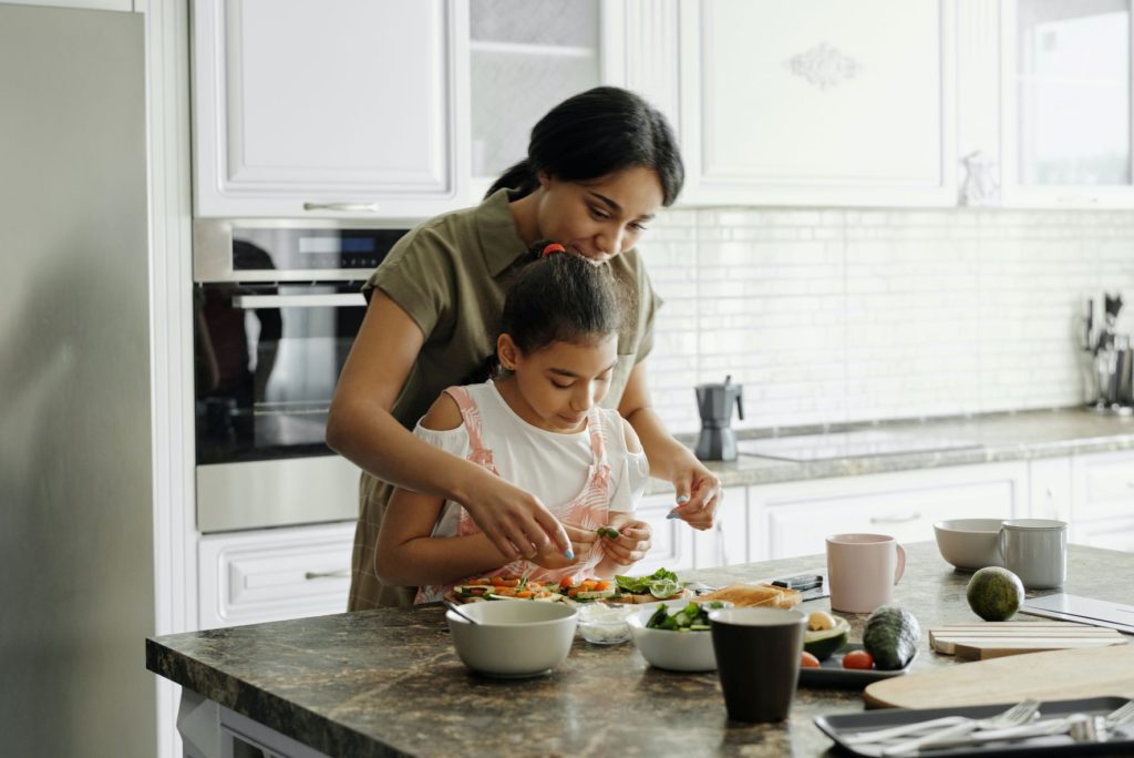 Mother and daughter cooking healthy food in kitchen