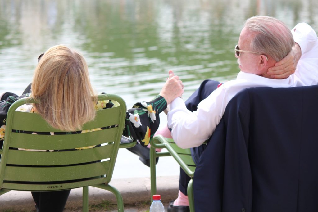 Elderly couple holding hands next to pond in Paris