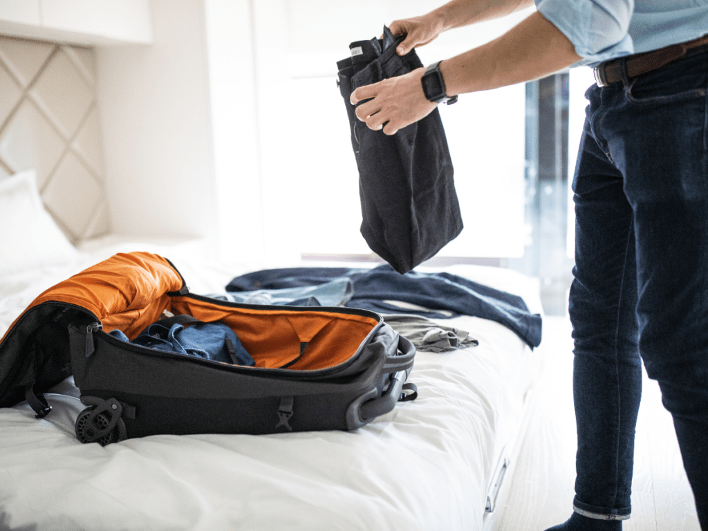 Man packing suitcase on bed