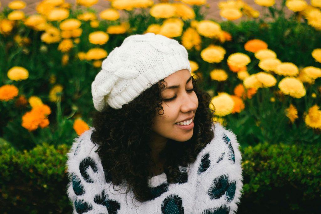 Young lady in hat relaxing and surrounded by flowers