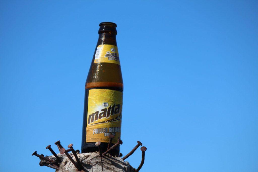 A Bottle of Jamaican Malta Drink perched on an old post