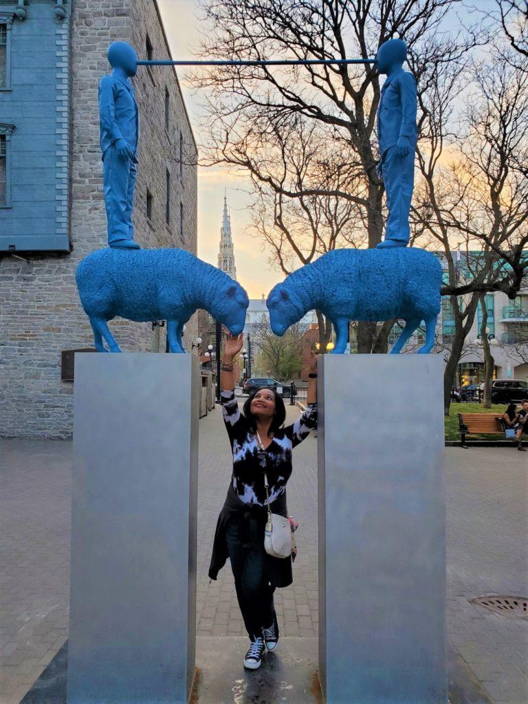 Monique Abbott standing at the "Our Shepherds" Statue created by Montréal-based artist Patrick Bérubé