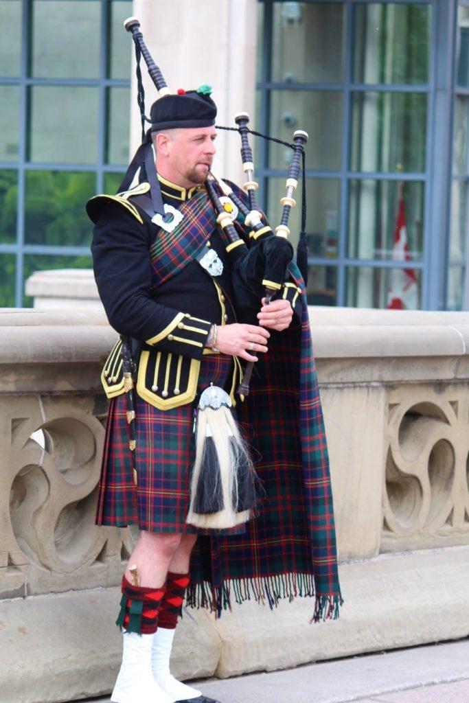 Man in Downtown Ottawa area playing bagpipe dressed in traditional Scottish costume