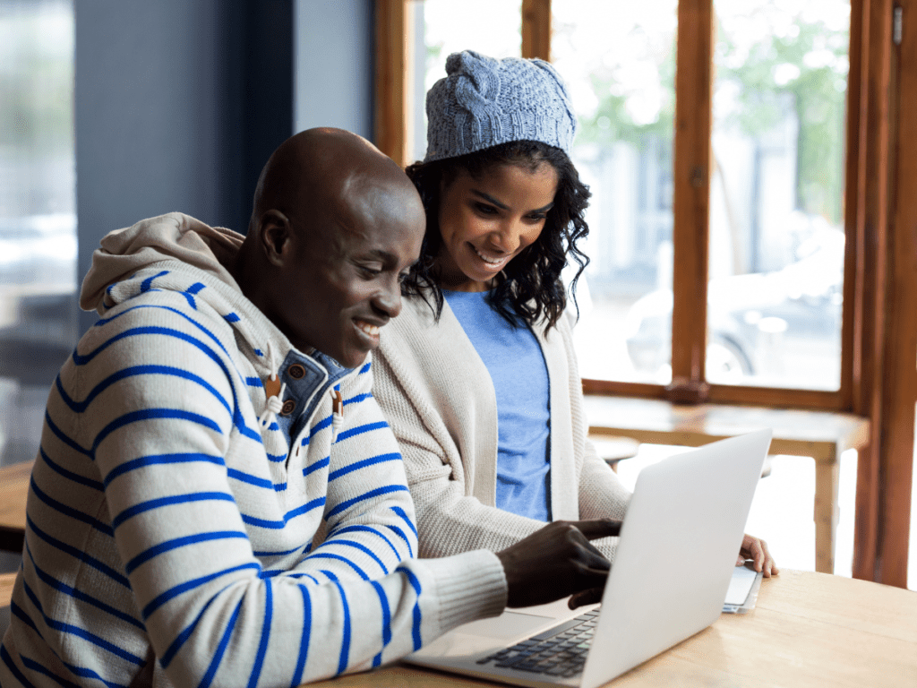 Couple wearing blue smiling while they look at laptop