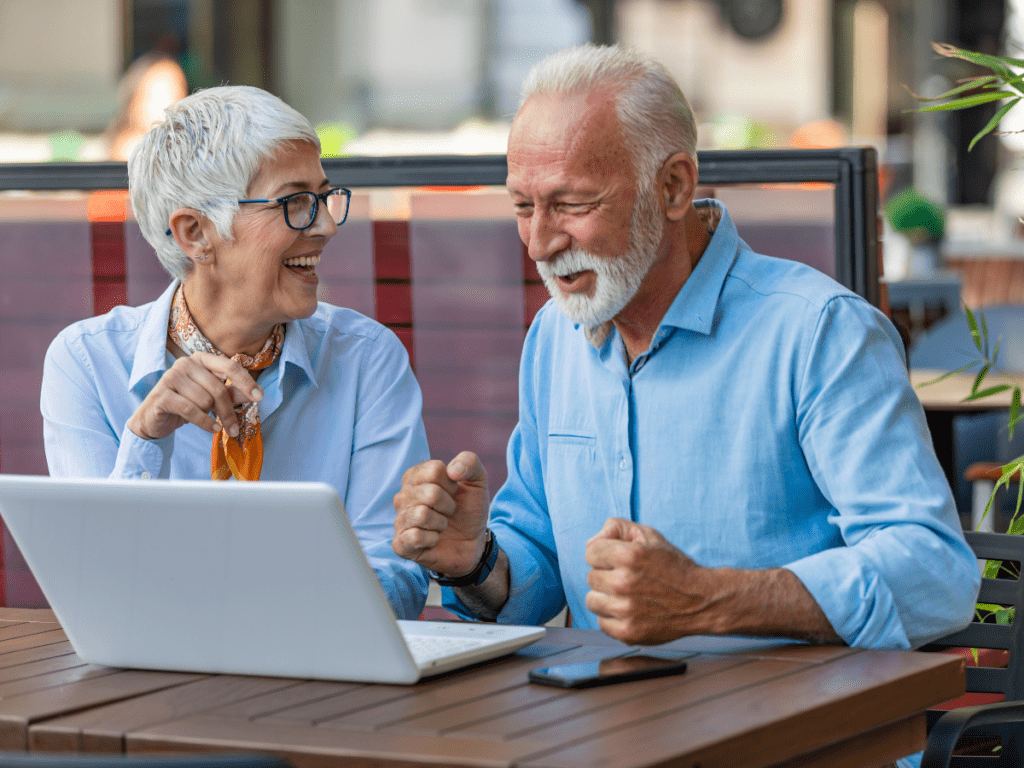 Elderly Couple laughing while reading from laptop