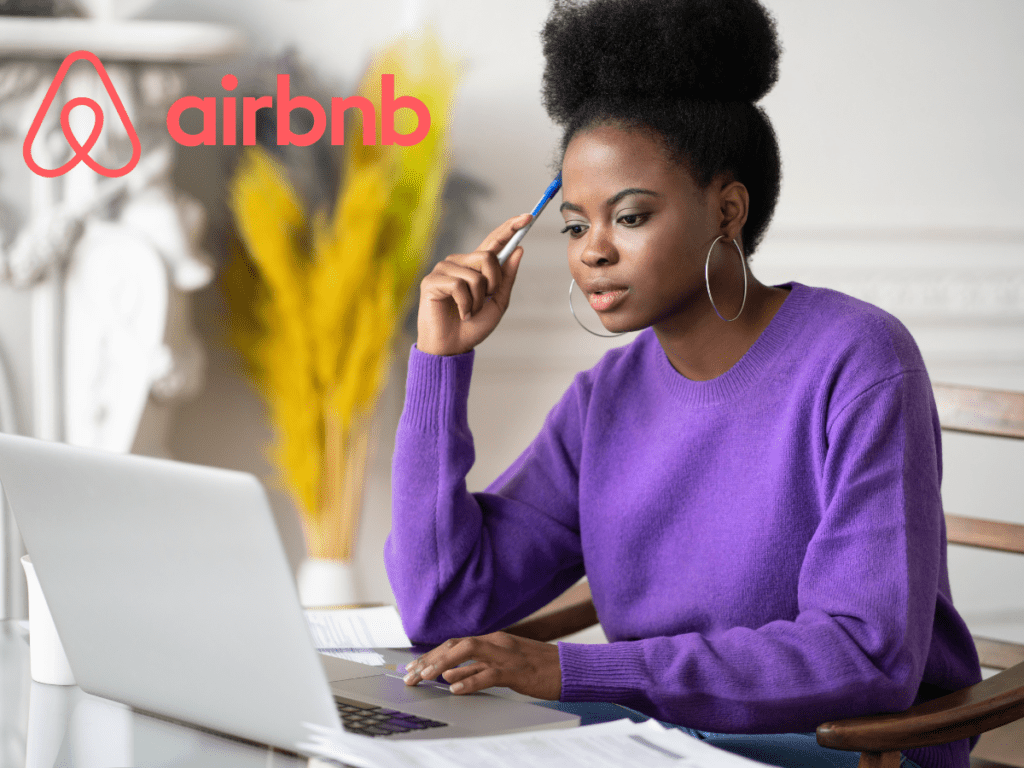 Woman wearing purple sweater working on laptop from desk