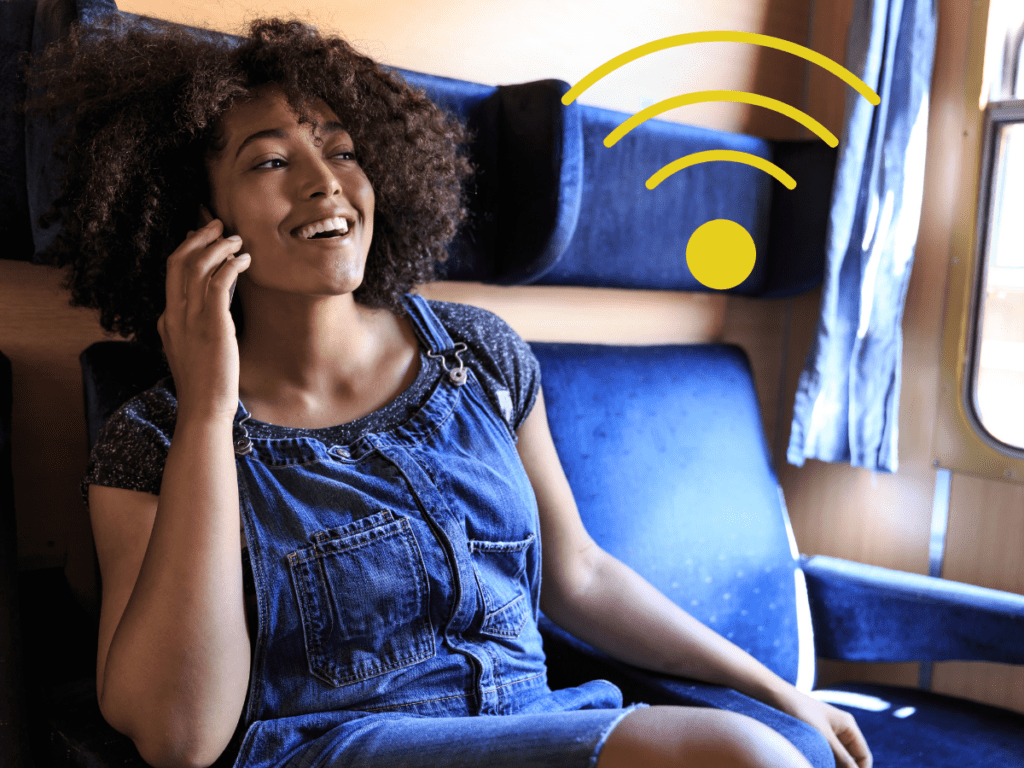 Woman in Blue Dress Seated Comfortably on Train Using Phone Connected to WIFI