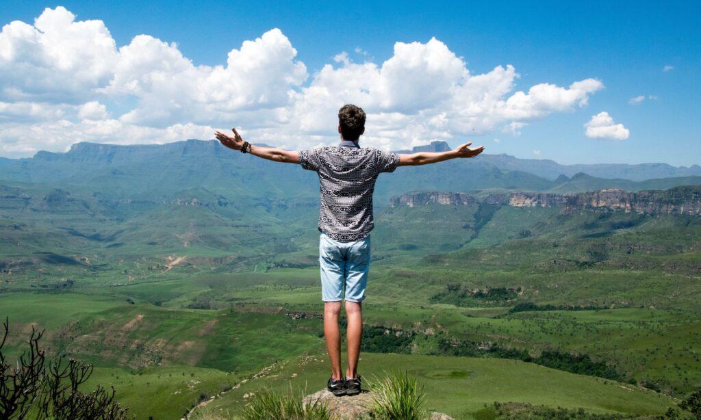 Man standing on rock with arms wide open symbolic of a purpose filled life