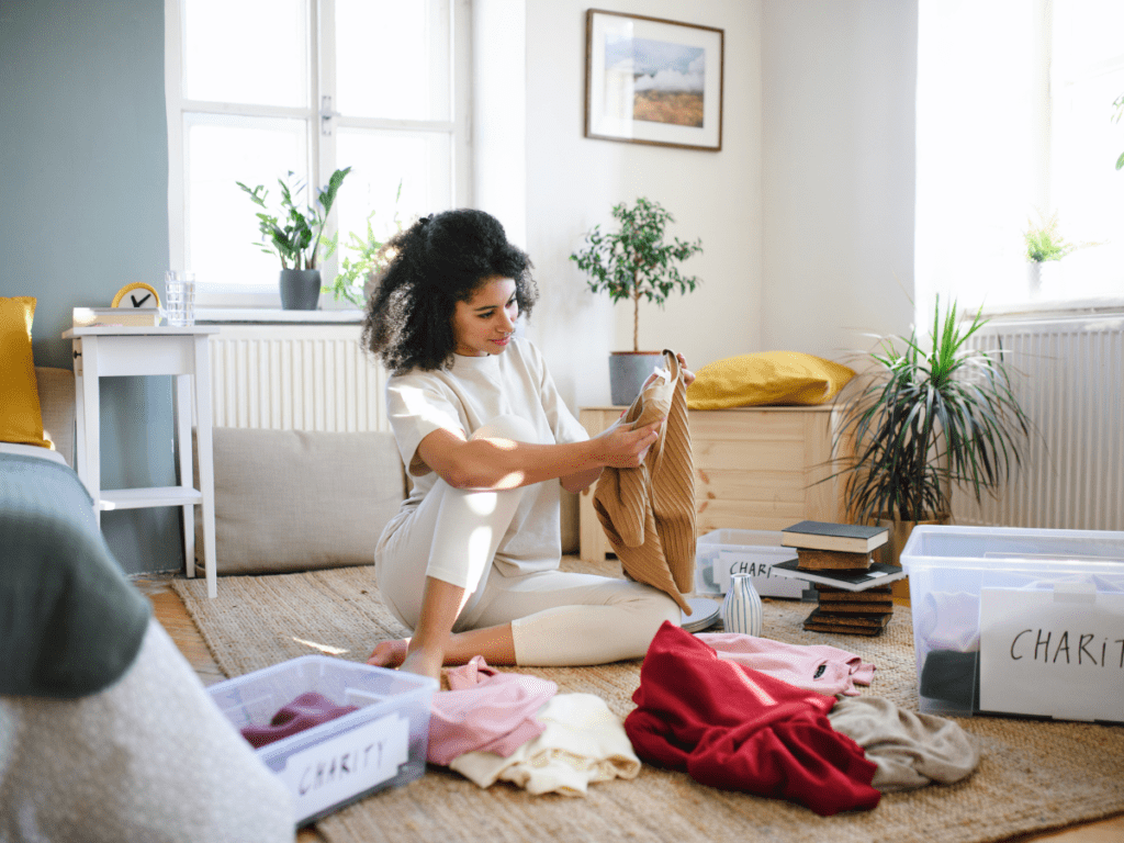A young lady sitting on floor packing boxes and decluttering her home