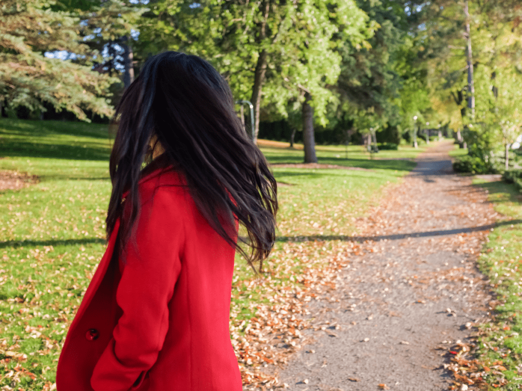 Woman dressed in read coat on a walking trail looking back